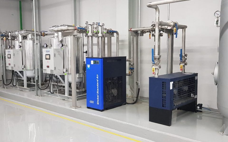 Desiccant air dryer system with adsorption regeneration cycle, inline filter, pressure gauge, automatic switching valve, and air compressor piping in industrial compressor room